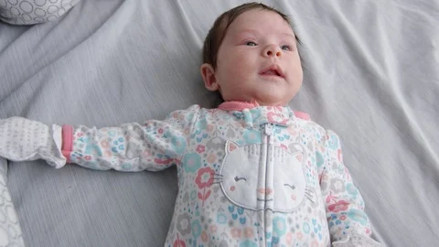 Slow motion of baby moving in bed wearing pajamas and hand mittens Stock Footage 107617115