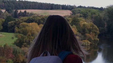 Slow motion back view of a woman with hair blowing in the wind, looking at .. Stock Footage 346720426