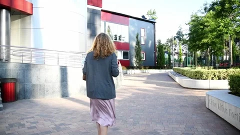 Slow motion back view of a young blonde business woman walking in morning 库存影片 332609811