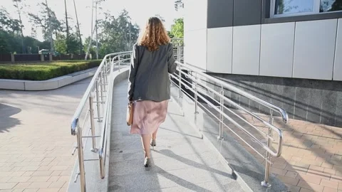 Slow motion back view of a young blonde business woman walking up a ramp 库存影片 333039632