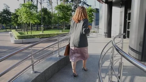Slow motion back view of a young blonde business woman walking up a ramp Vídeo Stock 333039636