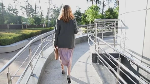 Slow motion back view of a young blonde business woman walking up a ramp Vídeo Stock 333039641
