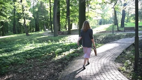 Slow motion back view of a young blonde woman walking through a park. Vídeos de archivo 333070335