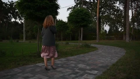 Slow motion back view of a young blonde woman walking through a park Vídeos de archivo 333070988