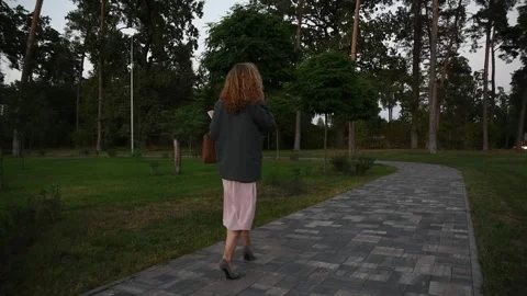 Slow motion back view of a young blonde woman walking through a park Vídeos de archivo 333071016