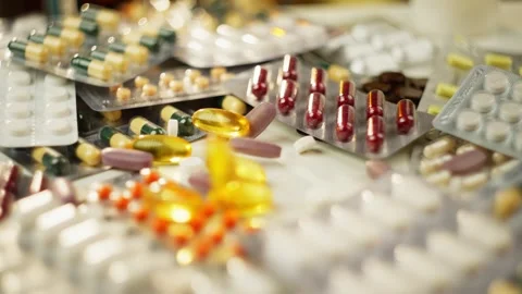 Slow Motion Background: Pills Falling onto Medicine Bottles and Boxes Stock Footage 278828618