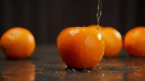 Slow motion background video of water pouring onto a juicy orange. Stock Footage 277999460
