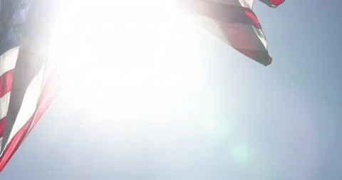 Slow Motion Backlit Real American Flag Waving In Wind Against a Deep Blue Sky Stock Footage 156265351