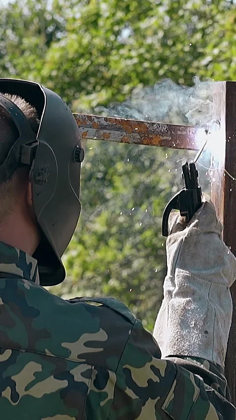 Slow motion backside man builds fence using tool at sparks Video stock 308008472