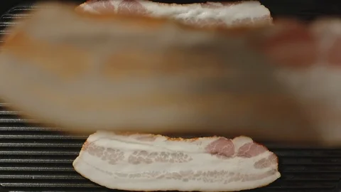 SLOW MOTION: Bacon slices falling to the grill - Top View Video stock 104482682