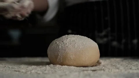 Slow Motion  bakery chef sprinkles flour over bread dough. Видео 143147202