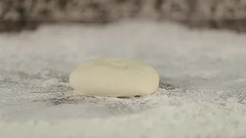 Slow motion ball of dough falls on flour on the table. Dough falls Stock Footage 134681693