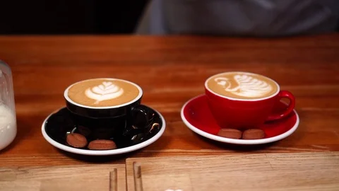 Slow motion on barista hand serving coffee art cappuccino on wooden car counter Stock Footage 104372072