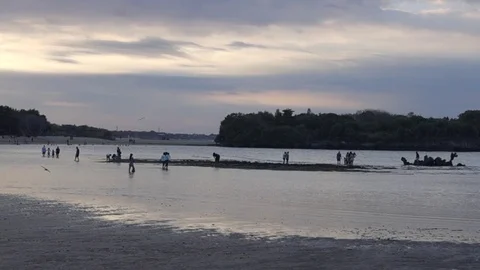 Slow-motion beach at sunset in Bali, people in silhouette playing in background Stock Footage 83098347
