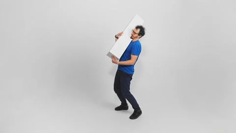 Slow motion of bearded Caucasian guy in casual clothes carrying long parcel in 스톡 동영상 322508411