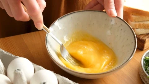 Slow motion of beating whisking mixing eggs with fork for scrambled eggs Stock Footage 125911540