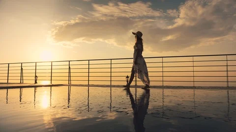Slow motion - Beautiful shot of a woman in a long flow dress walking by the pool Stock Footage