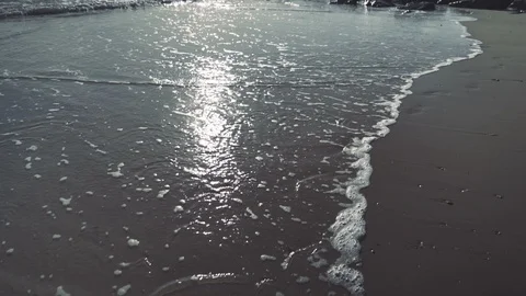Slow motion beautiful walking shot as waves lap beach with sun reflection v2 Stock Footage 119534218