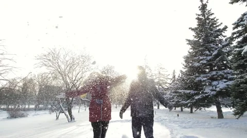 Slow motion. A beautiful young guy and a girl throws snow into the air. A Stock Footage 162084539