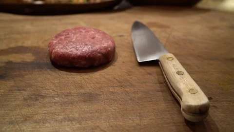 SLOW MOTION Beefburger on wooden worktop being seasoned ready for cooking, Vídeos de archivo 103345750