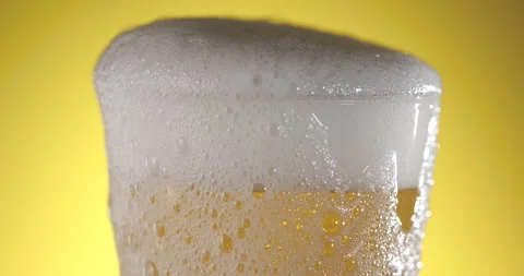 Slow motion of beer foam rising in a glass with bubbles and golden liquid Stock Footage 340482703