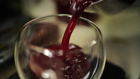 Slow motion berry tea pouring from pitcher into clear cocktail glass Stock Footage 311667490