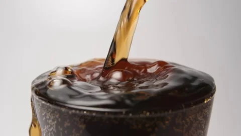 SLOW MOTION: Beverage overflows a glass on a white background - close up Stock Footage 70804342