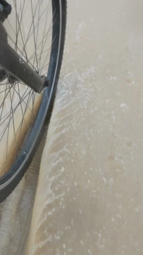 Slow Motion of Bicycle Wheel Splashing Through Puddle in Rain Stock Footage 308685641