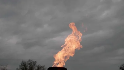 Slow motion of big orange fire of eternal flame with grey heavy sky on Stock Footage 114557466