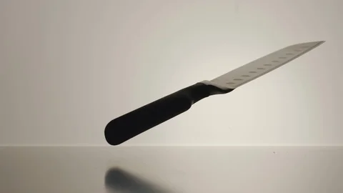 SLOW MOTION: Black cooking knife twisting on the white surface Stock Footage 101622085