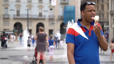 Slow motion of a black man walking while eating an ice cream cone Stock Footage 111877456