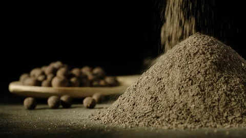 SLOW MOTION: Black pepper powder pouring in a heap next to black peppercorns Видео 107501570