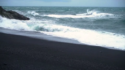 Slow motion black sand beach - waves crashing into cliff Видео 72332278