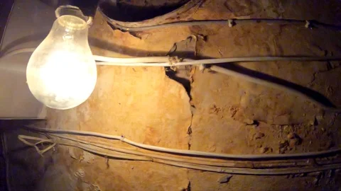 Slow motion of a blinking light bulb against a shabby wall and wires. Video stock 126792033
