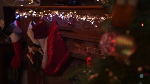 Slow motion, blond boy hangs two Christmas stockings on wood mantle Stock Footage 99399697