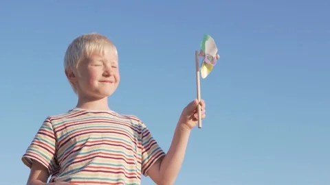 Slow motion a blond boy a spinning wind toy Stock Footage 108023325