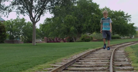 Slow Motion Blonde Haired Boy Walks on a Train Track Stock Footage 61522487