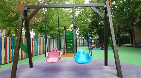 Slow motion of blue and pink swings swinging in empty playground Stock Footage 211814047