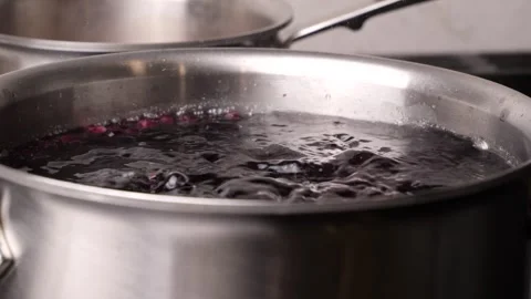 Slow motion boiling berries in a stainless steel pot Stock Footage 305941197