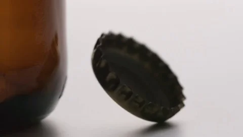 SLOW MOTION: Bottle cap falls near a brown bottle - macro shot Stock Footage 71568405