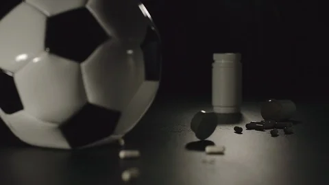 SLOW MOTION: Box of pills falls next to football ball and pills scatter around Stock Footage 108417434