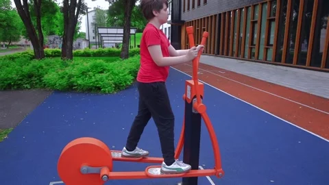 Slow Motion Boy Exercising on Outdoor Air Walker Machine i Stock Footage 338013827