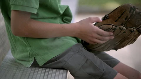 Slow motion of boy holding baseball mitt then setting it down next to him on Stock Footage 50488693
