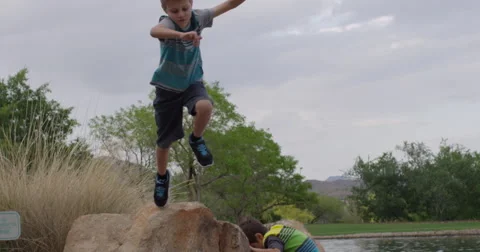 Slow Motion Boy Jumps Off a Boulder and Tumbles Stock Footage 61524260