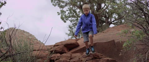 Slow Motion Boy Jumps Off Desert Rock and Runs Stock Footage 61836800