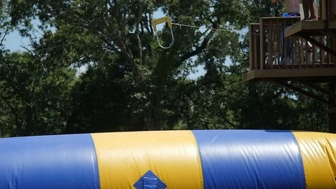 Slow-motion boy jumps on inflatable in lake Video stock 118724422
