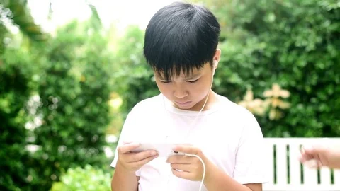 Slow motion boy play smartphone in garden and not happy Stock Footage 80295723