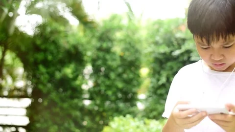 Slow motion boy play smartphone in garden Stock Footage 80555553