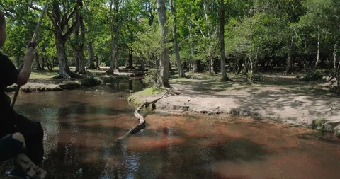 Slow motion boy on rope swing over forest river Stock Footage 116047493