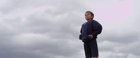 Slow Motion Boy Stands Bravely with a Cloudy Background Stock Footage 61838000